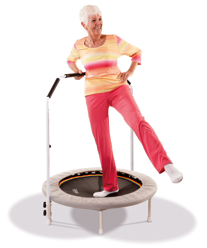 Seniorin trainiert mit der Hilfe eines Haltegriffes auf einem Trimilin Trampolin